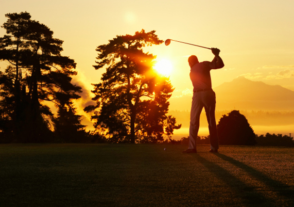 Un golfeur en ombre chinoise devant un coucher de soleil